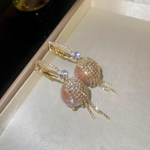 Macro detail of luxury gold tassel earrings with sparkling zircons on satin display