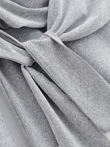 Detail of soft grey knit fabric dress featuring a stylish knotted waist tie detail