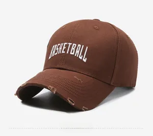 Detail of dark brown cotton baseball cap showing distressed brim and white basketball embroidery