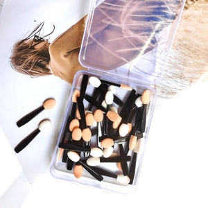 Macro detail of double-sided disposable eye shadow brushes in a clear plastic box