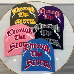 Five assorted jacquard knit beanies with lightning design on marble background