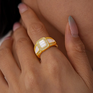 Gros plan d'une bague dorée ornée d'une pierre blanche rectangulaire et de cristaux
