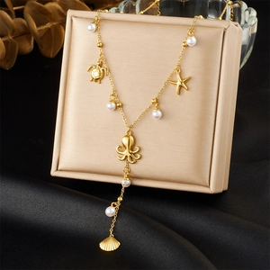 Detailed view of gold Y-chain necklace with octopus, turtle, and starfish charms on silk