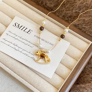 Golden rocking horse necklace with pearls and tiger eye stones on jewelry tray