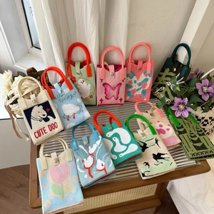 Assorted cute knitted mini handbags with cartoon dog and floral patterns on wicker table