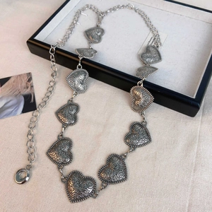 Close-up of vintage heart-shaped metal waist chain with intricate floral carvings in silver