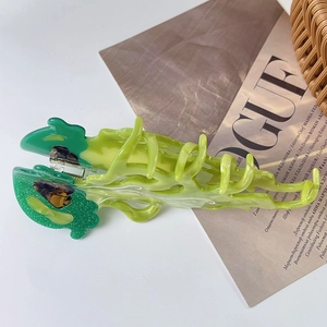 Close-up of green acetate jellyfish hair claw clip with brown amber detail and metal spring