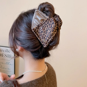 Detail of leopard print fabric and leather hair claw clip worn on a bun hairstyle