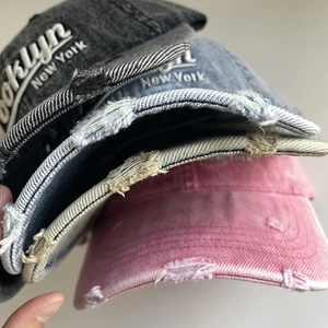 Detail of distressed brim and Brooklyn embroidery on washed denim baseball caps