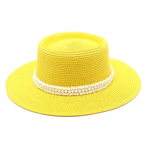 Detailed view of yellow woven straw sun hat with elegant white pearls and lace ribbon decoration