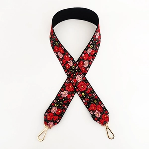 Close-up of wide black shoulder strap with red floral embroidery and gold metal clips