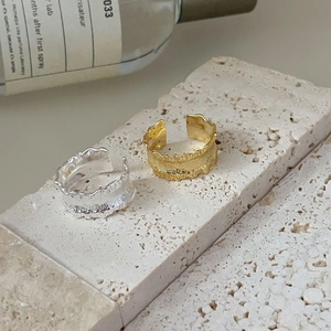Macro view of irregular lava texture gold and silver open rings on stone base