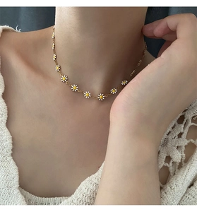 Detailed close-up of golden daisy necklace charms with white petals on a lace top