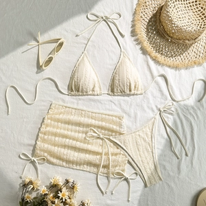 Flachbild eines cremefarbenen dreiteiligen Bikinis mit Strukturstoff und Minirock