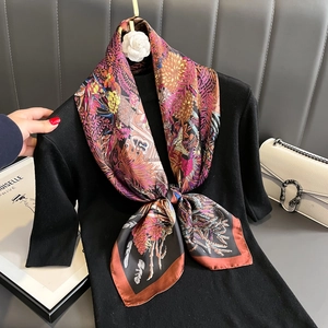 Floral print silk scarf with red border displayed on a black dress and gold hanger