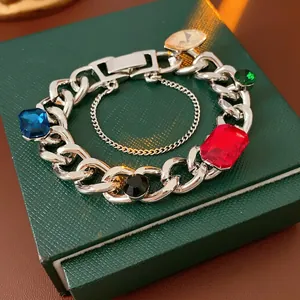 Silver link bracelet with colorful faceted gems on a dark green jewelry box
