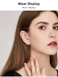 Close-up of overlapping star moissanite earrings in 925 silver on a female model's ear