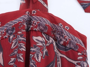 Détail d'une robe en mousseline rouge avec texture plissée et imprimé floral rétro