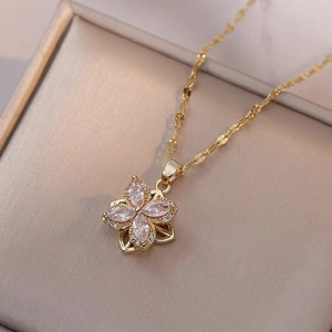 Detailed shot of rotating clover pendant with clear gems on golden titanium steel necklace