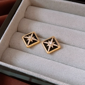 Macro shot of 16K gold plated diamond-shaped stud earrings with black enamel and star stones