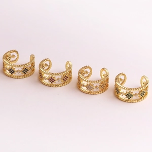 Detail of four gold ear cuffs with multicolored zircon stones in a minimalist layout