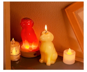 Detail of cute puppy-shaped candles in red and cream on a warm glowing wooden base
