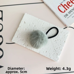 Detail of a 5cm light grey pom pom hair tie with high elastic band on a stone base