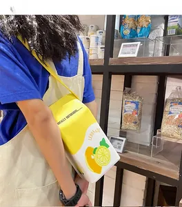 Lemonade milk carton cross-body bag worn by a model in a casual lifestyle supermarket setting