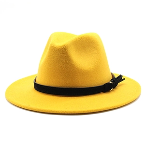 Dettaglio di un cappello fedora giallo in lana con fascia nera decorativa e fibbia metallica