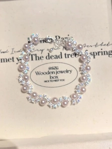 Detail of pink pearl bracelet with zircon flower accents on jewelry display card