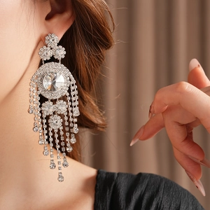 Dettaglio di orecchini vintage in argento con nappe e strass indossati da una modella