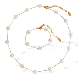 Elegant gold stainless steel jewelry set featuring necklace and bracelet with white pearls