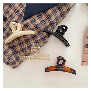 Flat lay of four hollow geometric hair claws in ivory, black, clear, and tortoiseshell
