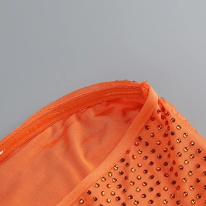Détail de tissu orange à strass et fermeture éclair sur une robe de soirée moulante