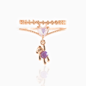 Detail of rose gold ring with heart charm and small bear holding a purple zircon stone