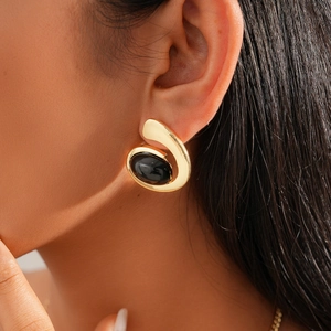 Close-up of gold geometric oval stud earring with black resin inlay on model