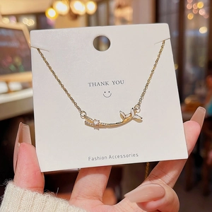 Elegant gold-tone fishtail necklace with diamond accents on a white display card
