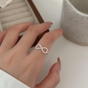 Detailed view of s925 silver infinity ring with beaded texture worn on model's finger