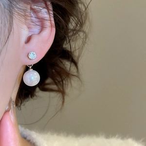 Close-up of elegant pearl and zircon earrings worn by a model in soft lighting