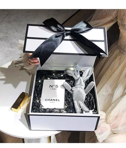 White rectangular gift box with black ribbon bow and shredded paper filler detail