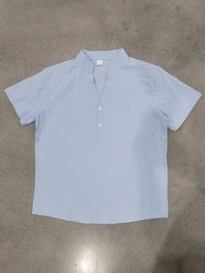 Flat lay of light blue linen short sleeve shirt on textured grey industrial background