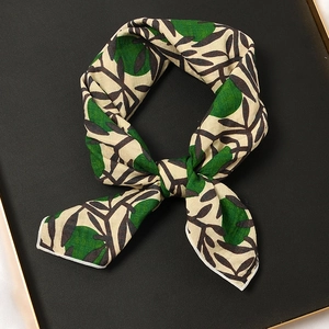 Carré de soie beige à pois verts et motifs de feuilles noires sur plateau en cuir