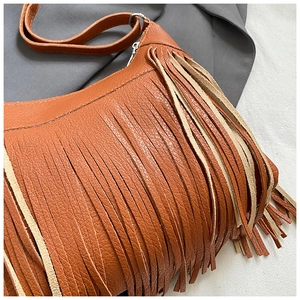 Detailed close-up of brown leather bag showing lychee grain texture and silver tassel accents