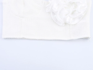 Gros plan sur un top blanc en mesh avec une grande fleur 3D en satin et sa texture