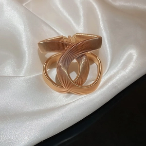 Luxurious gold textured metallic cuff bracelet with interlocking design on white silk