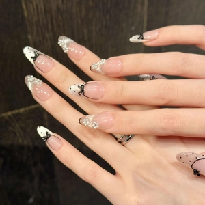 Macro shot of French almond press-on nails with 3D black bows and pearl accents