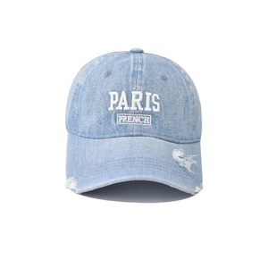 Detail of light blue washed denim baseball cap with white Paris embroidery and distressed brim