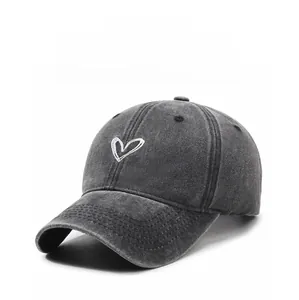 Close-up of hand-drawn heart embroidery on washed dark grey denim cotton baseball cap