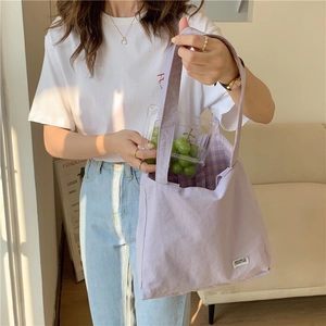Detalle de bolso tote de lona lavanda con forro de cuadros vichy y etiqueta tejida