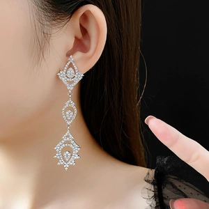Close-up of elegant long silver drop earrings with pavé zircons on a female model